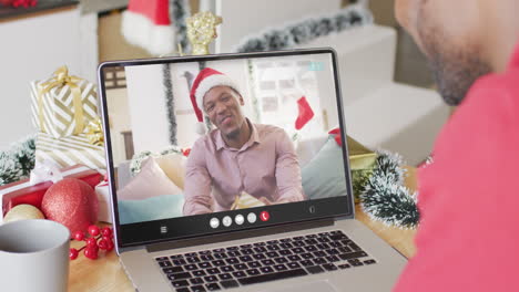 hombre afroamericano con decoraciones de navidad haciendo una llamada de video con hombre afroamericano