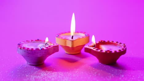 primer plano de las velas coloridas que queman celebrando diwali sobre un fondo púrpura