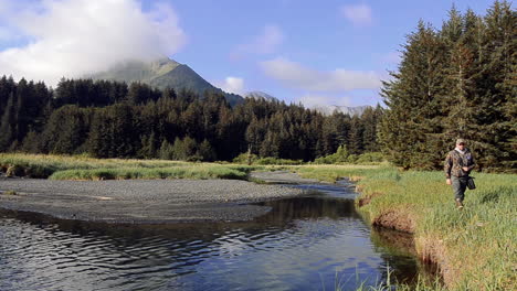 A-nature-and-wildlife-photographer-hiking-to-a-photoshoot-in-the-wilderness-of-Kodiak-Island-Alaska