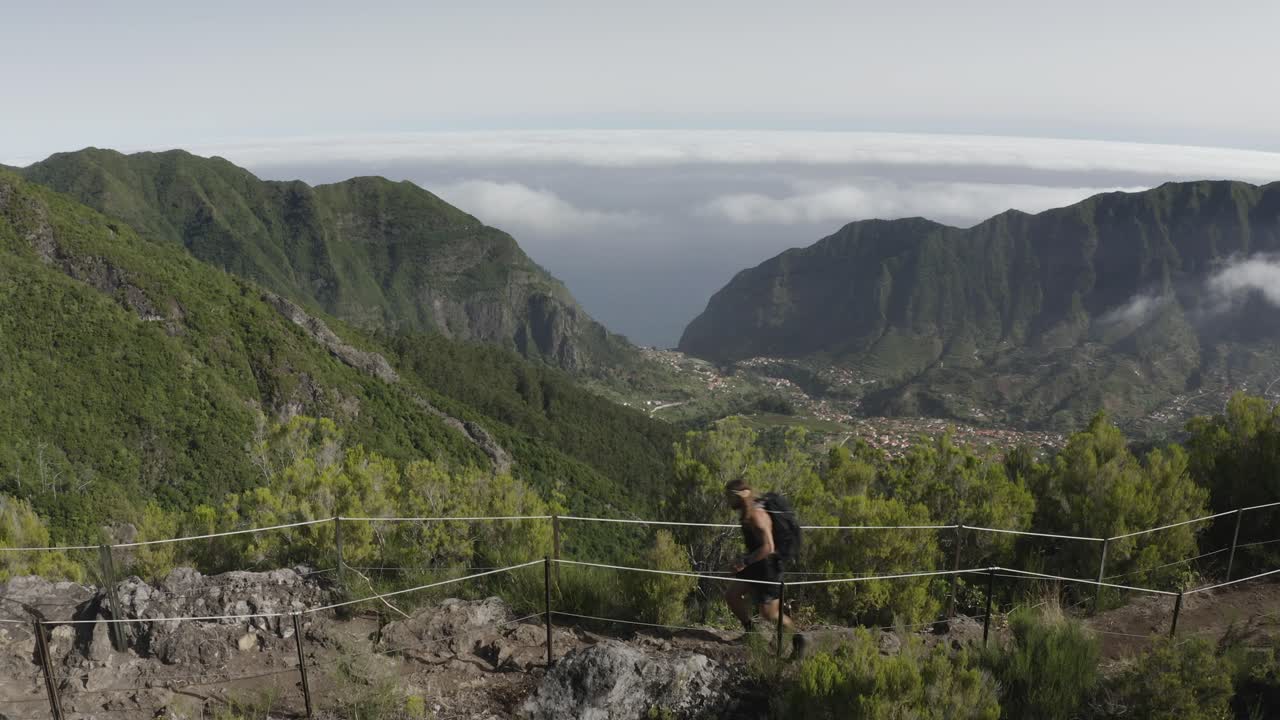 toma de drone del paisaje en caminho do pinaculo e foldhadal en madeira con un hombre fuerte y en forma caminando por el camino rocoso en la parte superior