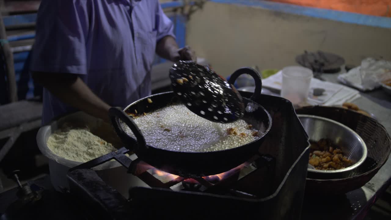 The battered food has just been dropped into the boiling oil which bubbles and is stirred at the night market.