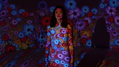 woman illuminated by colorful flower projections in an art installation
