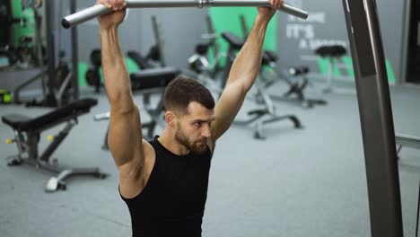 entrenamiento masculino de los músculos de la espalda y las manos haciendo ejercicios con pesas en un gimnasio