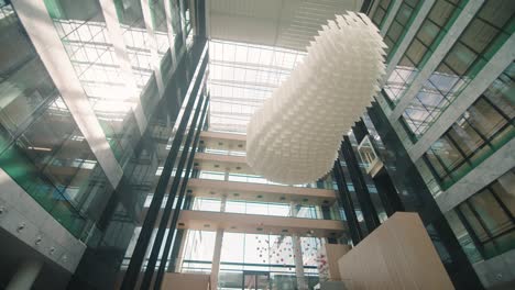 low angle shot of a crystal chandelier cascades hanging along high roof of a building with glass walls