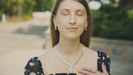 charming female caucasian model wearing printed chiffon tops and elegant jewelry set posing in front of the camera - rack focus slow motion