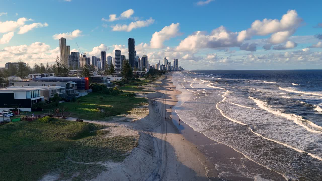 Aerial view of Gold Coast beach with people jogging and walking, under clear skies and bright sunlight