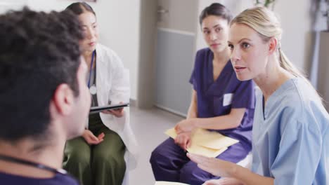 video of caucasian female doctor talking with diverse medical colleagues in hospital meeting