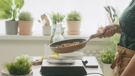 anonymous person frying walnuts in pan in kitchen