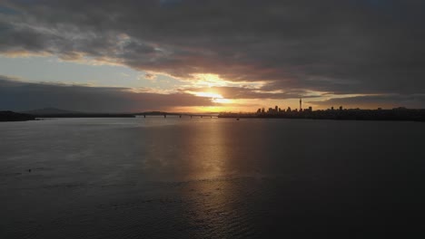 aerial, sunrise over auckland harbour bridge and cbd skyline in new zealand