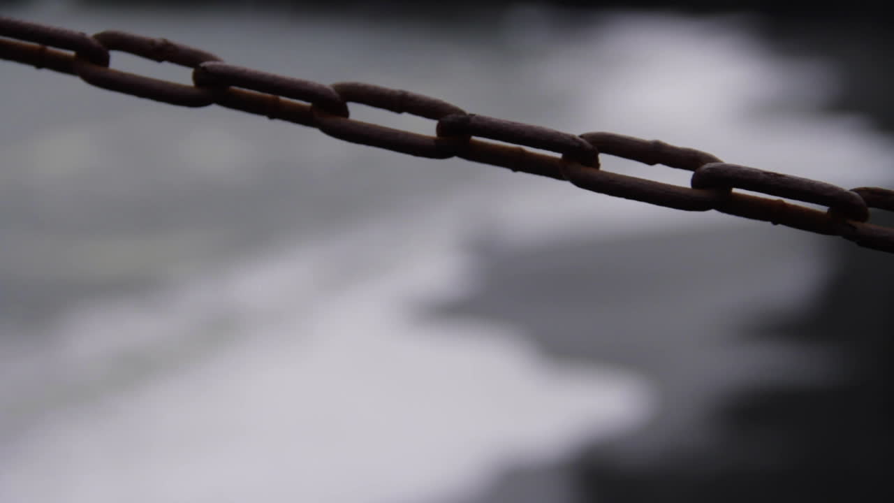 전경에 체인이 있는 아이슬란드 검은 모래 해변의 해안에 파도가 튀다