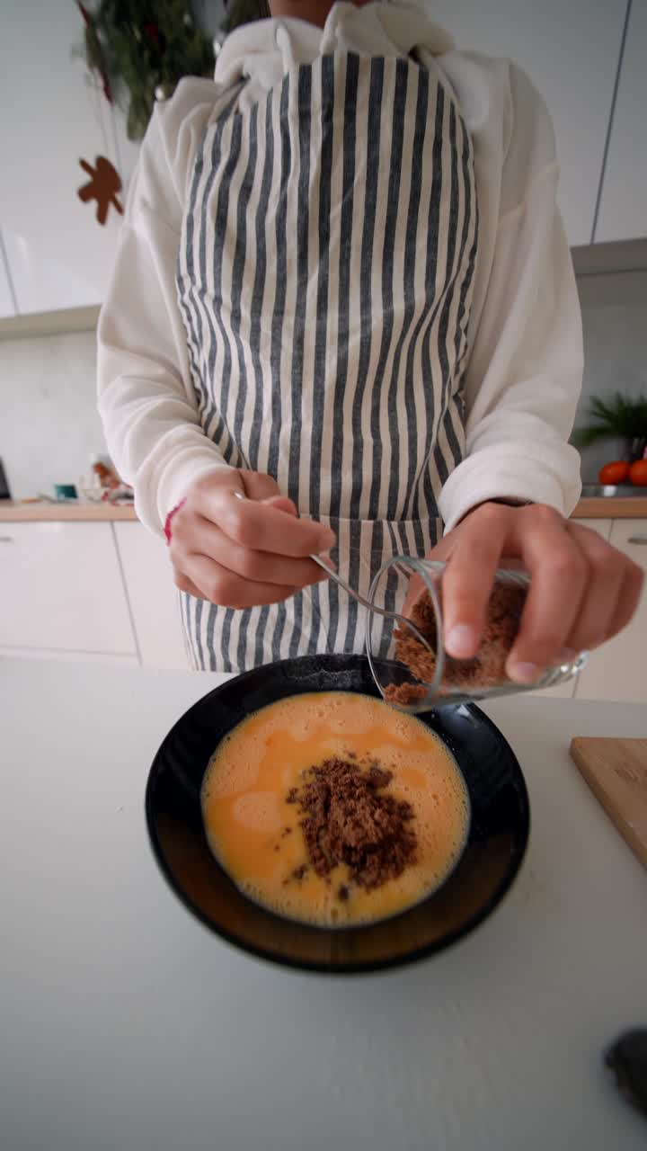 Giovane donna che aggiunge zucchero di canna alle uova in una cucina moderna.