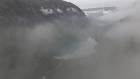 pure mountain lake while flying through fluffy cloudscape