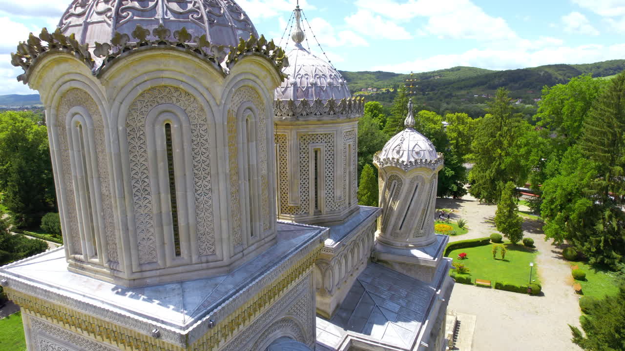Aerial drone view of the Curtea de Arges Monastery in Romania. Multiple people in front of it, gardens around