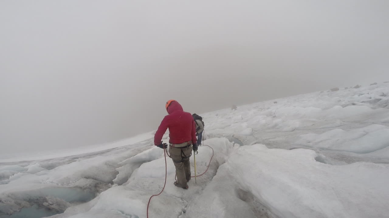 Hiker POV looking at rope and two other adventurers ahead at the freezing top of an Andean mountain - Cocuy