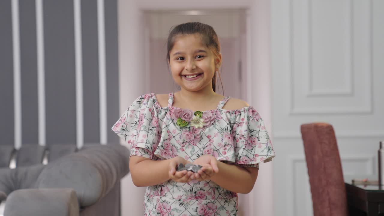 niña india feliz sosteniendo muchas monedas en su mano