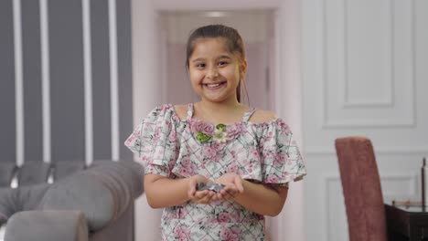 Happy-Indian-kid-girl-holding-lot-of-coins-in-her-hand