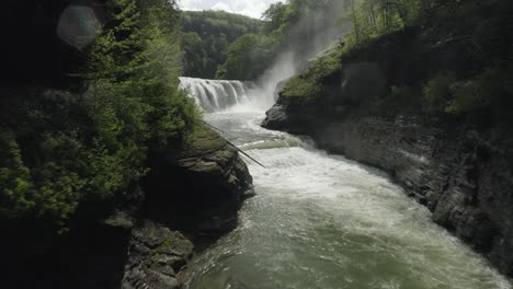 drone shot, flying through a canyon, revealing a beautiful waterfall