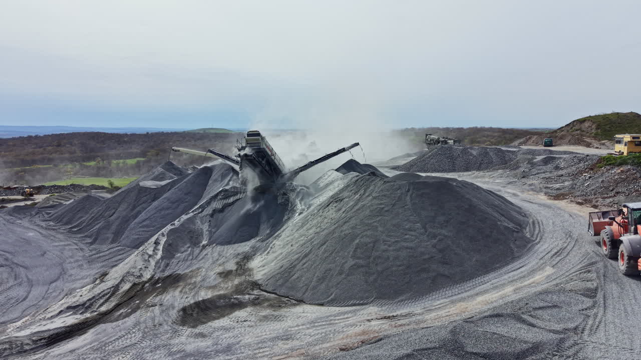 Pekerja mengangkut granit dari tumpukan besar di tambang di daerah terpencil pada hari berawan.