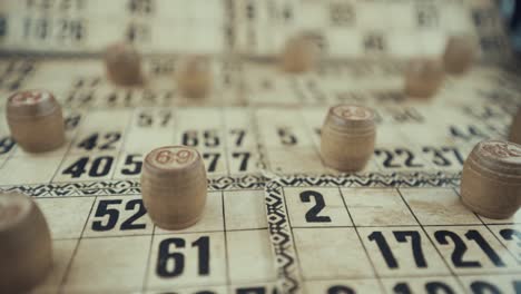 Macro-video-of-a-Bingo-board,-studio-lights,-120-fps,-slow-motion,-wooden-chip-digits,-Raw-footage,-lottery-desk-game,-card-numbers,-crane-slide-right-movement