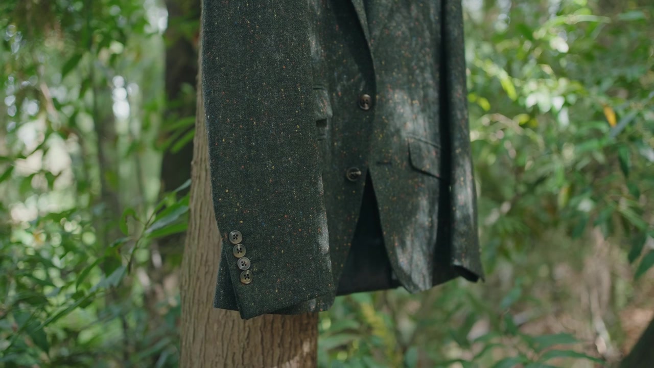 Formal suit jacket placed on tree trunk surrounded by natural green foliage