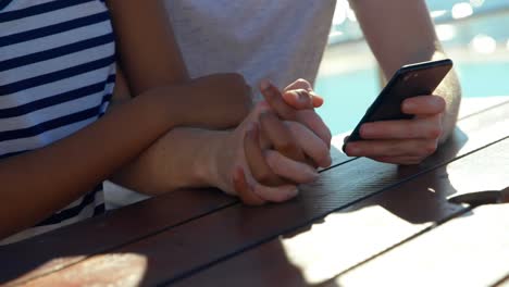 Close-up-of-couple-using-mobile-phone-on-table-4k