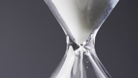 video of close up of hourglass with sand pouring, copy space on black background