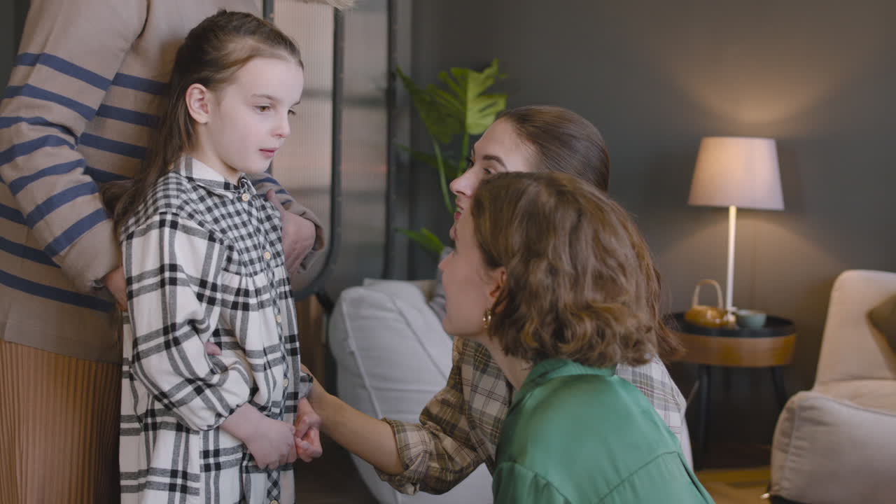 Bambina che parla con la madre e la zia mentre la nonna la abbraccia da dietro durante una riunione di famiglia a casa