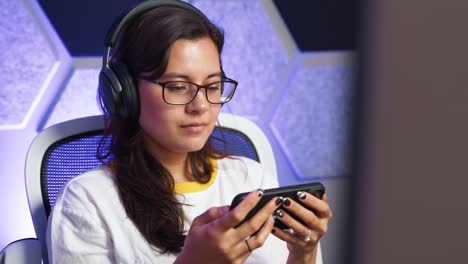 una mujer asiática con gafas viendo un video en un teléfono inteligente que la hace sonreír.