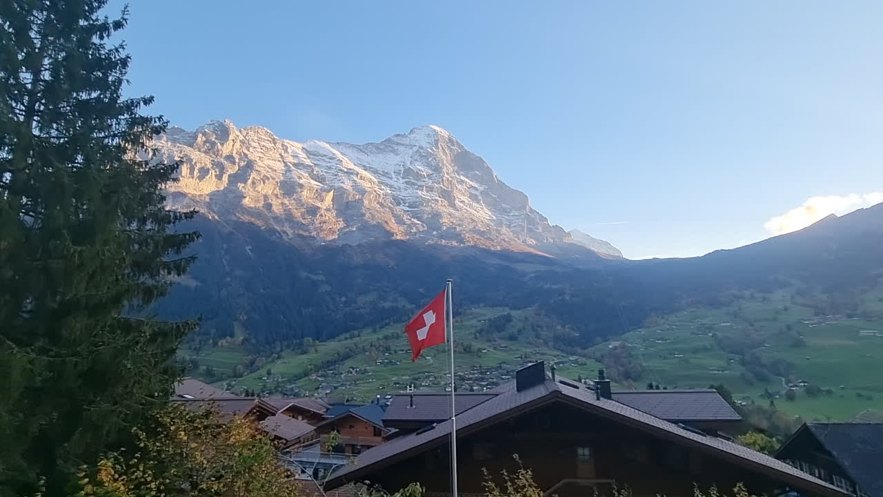 Villaggio svizzero pittoresco immerso in una valle verde sotto le Alpi innevate all'alba