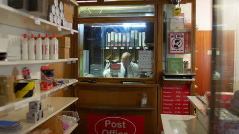 a post master in a post office labelling parcels behind the shop counter