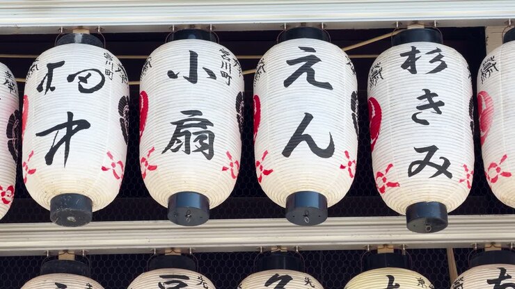 Inquadratura media fissa di lanterne di carta bianche con calligrafia kanji nera in un santuario di Kyoto
