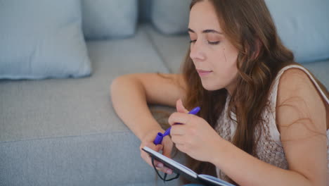 woman writing in notebook by sofa