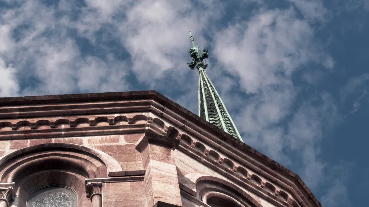 Cenevre'de, beyaz bulutlu mavi bir gökyüzüne karşı bir katedral kulesi ve dekoratif taş çatı hattının yakın çekim görünümü. Sabit çekim.