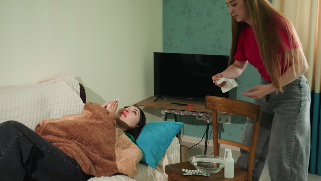 Женщина, чувствующая себя нехорошо, лежит на диване в уютной домашней обстановке. Женщина, испытывающая дискомфорт, отдыхает на диване, а помощник предлагает ей воду и оказывает поддержку в спокойной жилой обстановке.