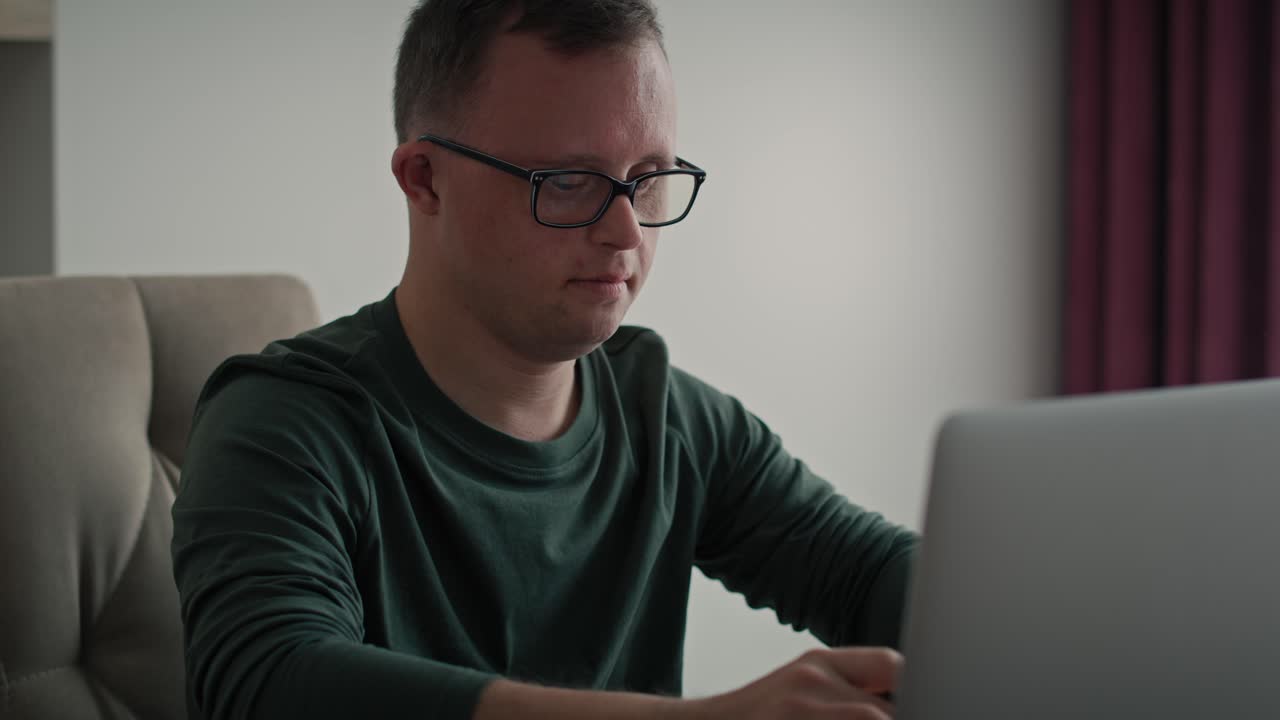 Focus adult caucasian man with down syndrome using laptop at home.
