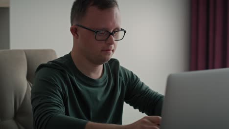 focus adult caucasian man with down syndrome using laptop at home.