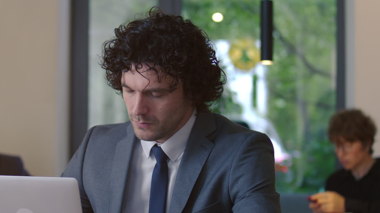 Focused Businessman Drinking Coffee and Using Laptop in Cafe