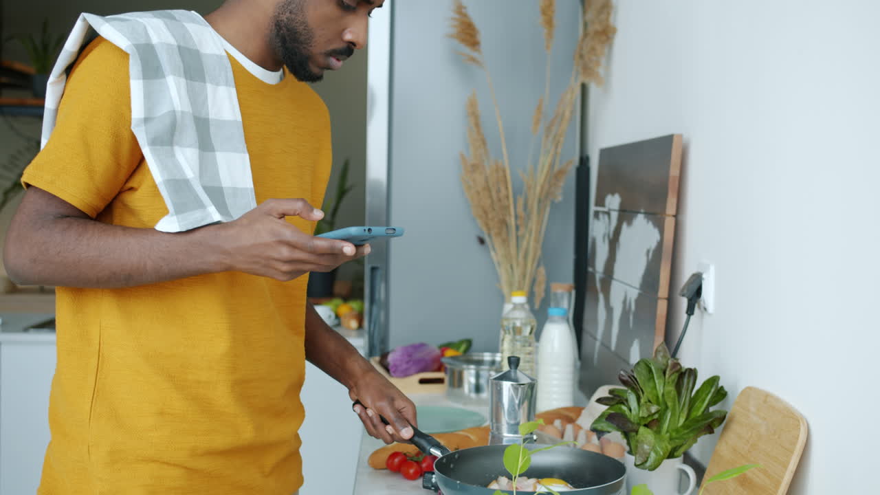 Man Cooking in Kitchen Using Smartphone