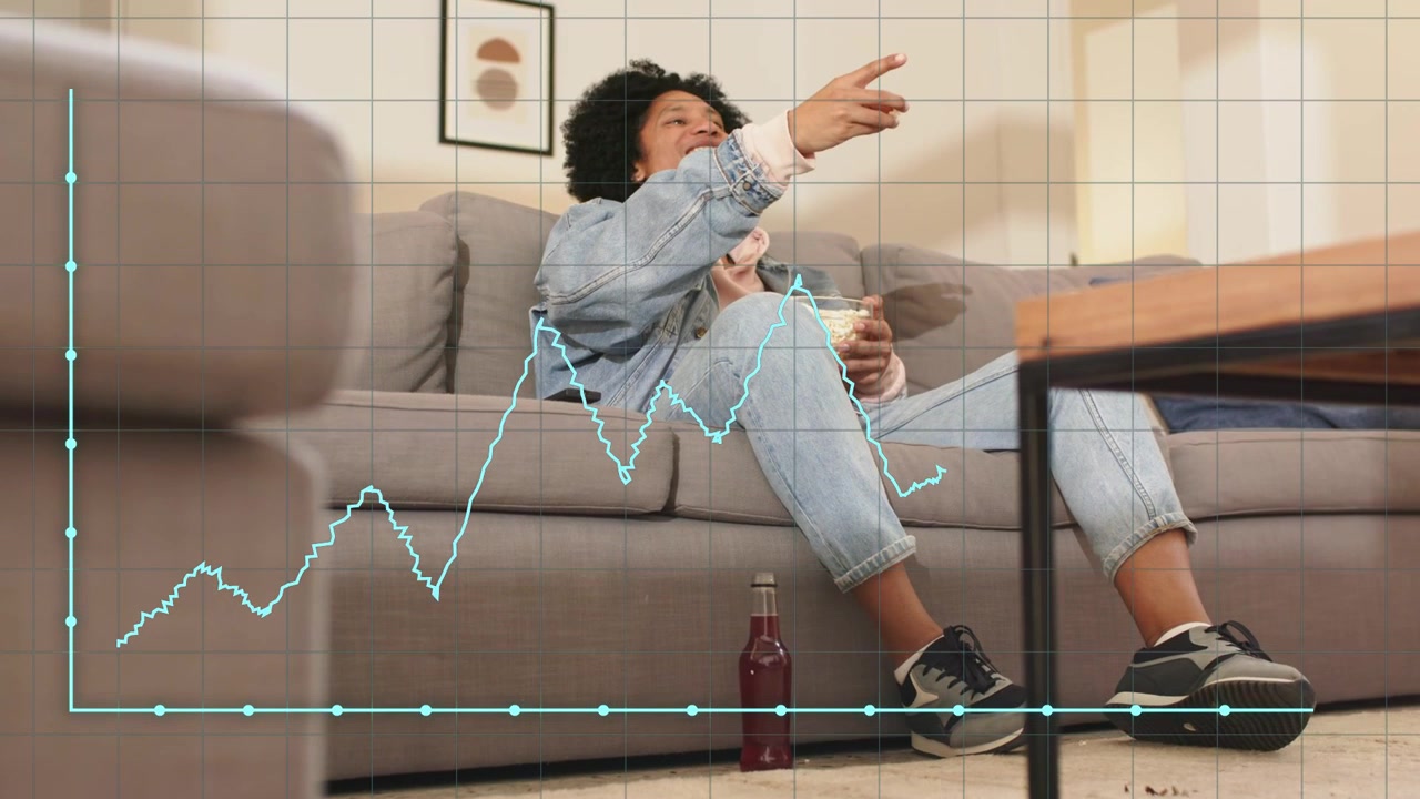 Donna seduta su un divano grigio che tiene un telecomando e una ciotola, che guarda un grafico finanziario irregolare in aumento, sorridendo