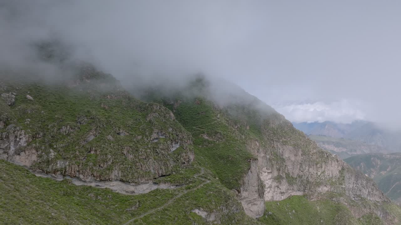 Cinematic drone footage flying low over a rugged trekking trail in the Peruvian Andes. The narrow path cuts through mist and mountain terrain, ideal for adventure, hiking, or travel storytelling.