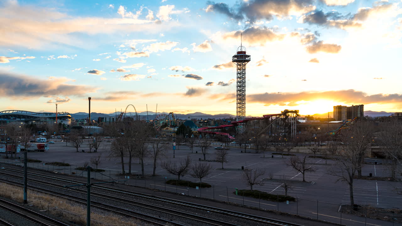 timelapse sobre las vías del tren de un atardecer vívido detrás de los jardines de elitch, denver