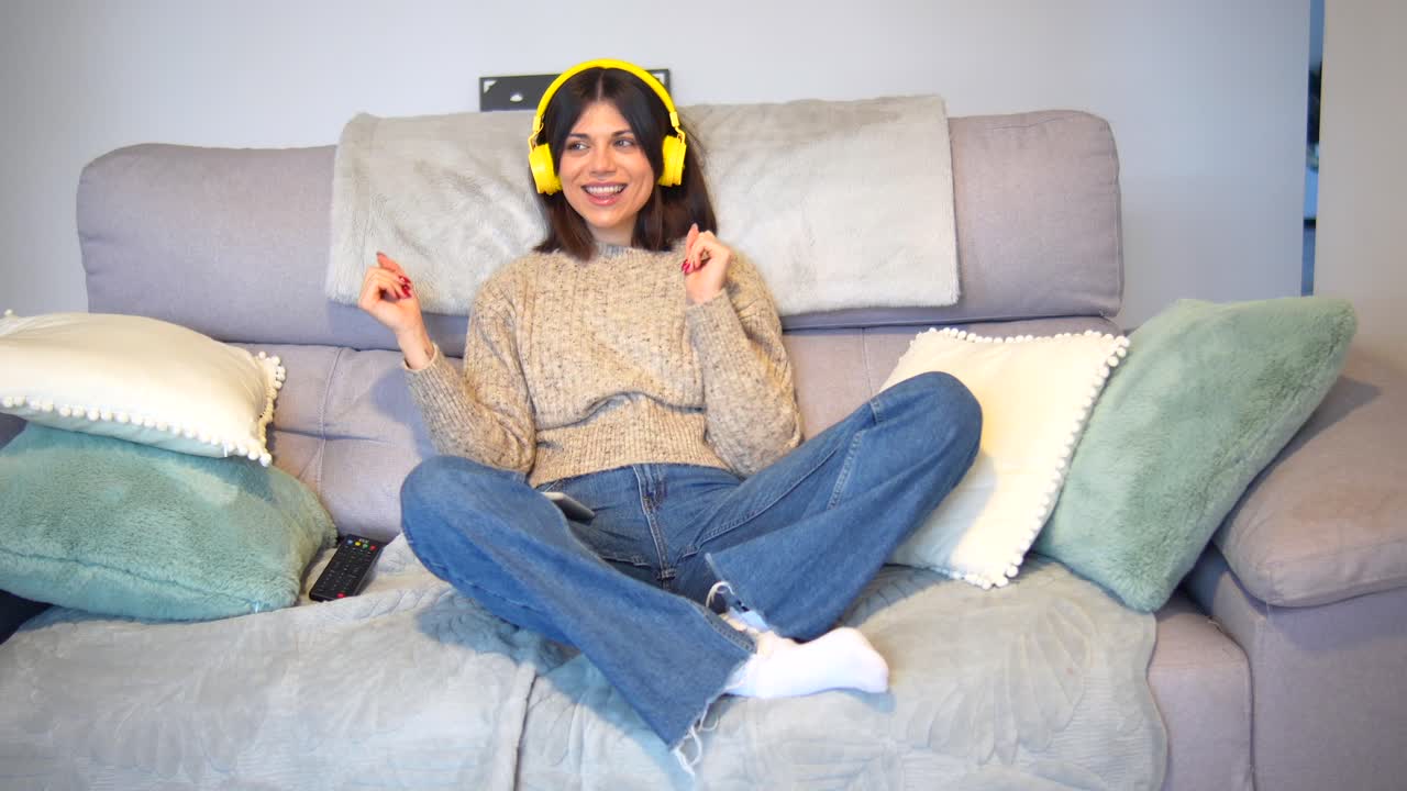 Woman listening to music on couch with headphones