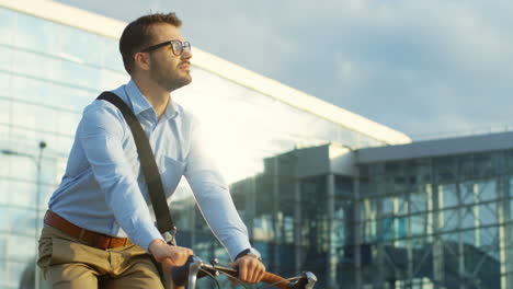 retrato de un hombre atractivo con gafas y montando en bicicleta, mirando a los lados y pensando