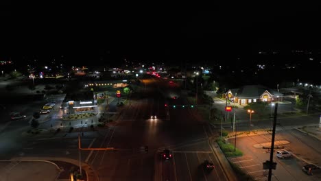 main street of american city with traffic at night. mc donalds restaurant and other fast food buildings in virginia, usa. aerial backwards wide shot.