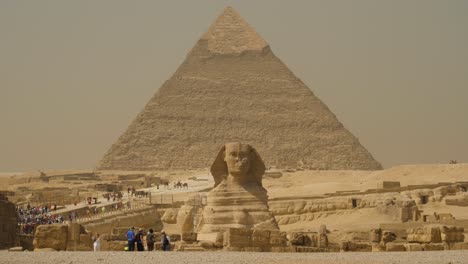 Die-Große-Sphinx-Mit-Der-Gewaltigen-Pyramide-Von-Gizeh-Im-Hintergrund-Und-Massen-Von-Touristen,-Die-Diesen-Historischen-Ort-Besuchen