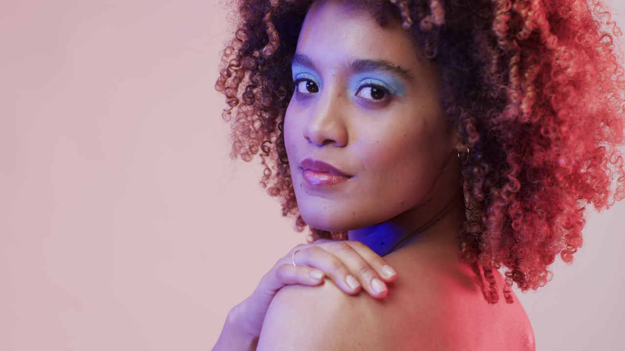 mujer biracial con cabello oscuro en luz azul y rosa con espacio de copia, cámara lenta