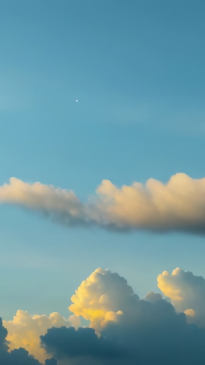 Vertical video: Lighting cumulus clouds as sun lowers at sunset, with white dot drifting