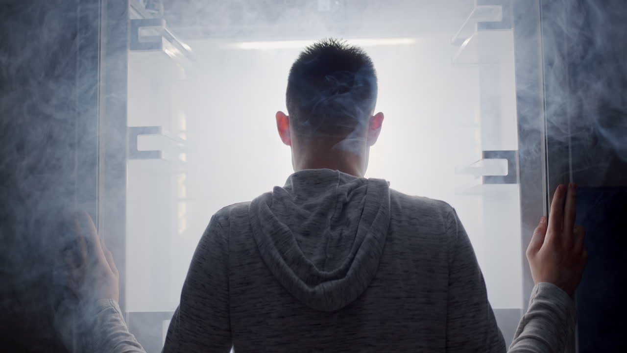 한 남자가 빛과 안개가 나오는 빛나는 냉장고를 들여다본다