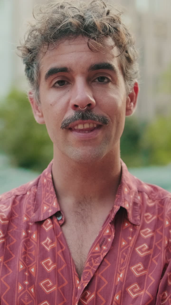 Homem com bigode e piercing no nariz sorrindo para a câmera