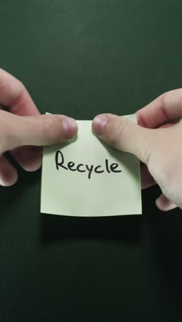 hands posting recycle sticky note on dark green wall, presenting eco awareness